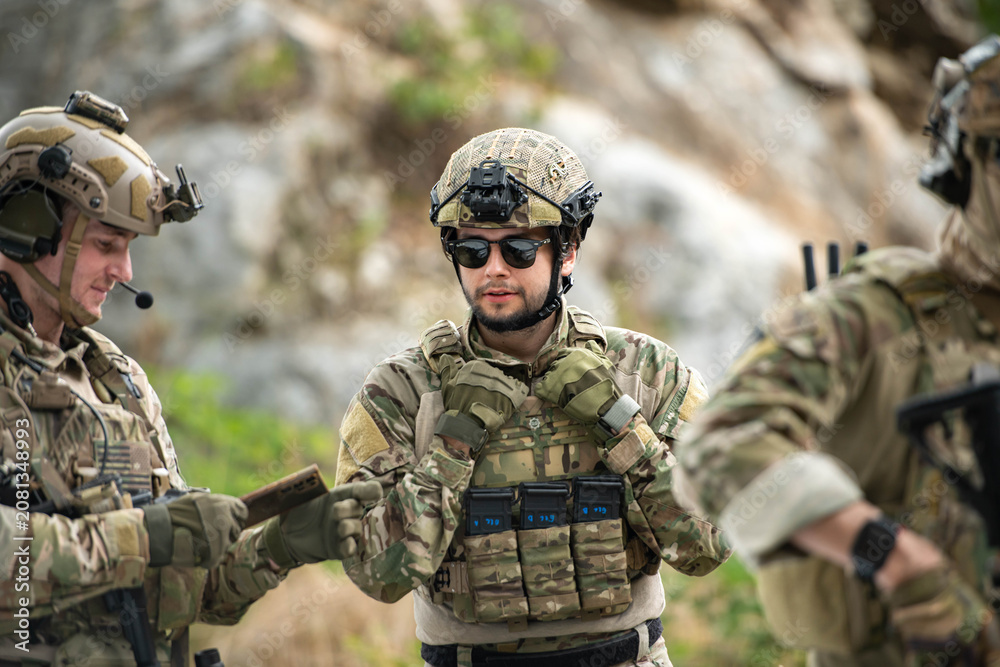 Fototapeta premium Military personnel discuss equipment and mission details during a tactical field briefing
