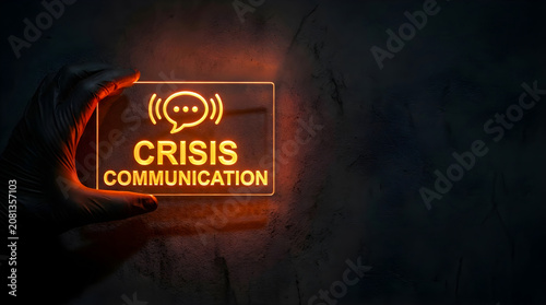 Gloved hand holding glowing crisis communication sign for emergency management