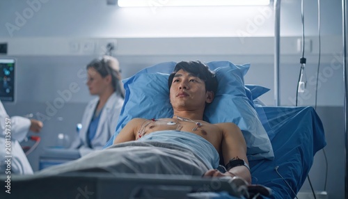 Young man undergoing medical monitoring with electrodes attached in a hospital bed