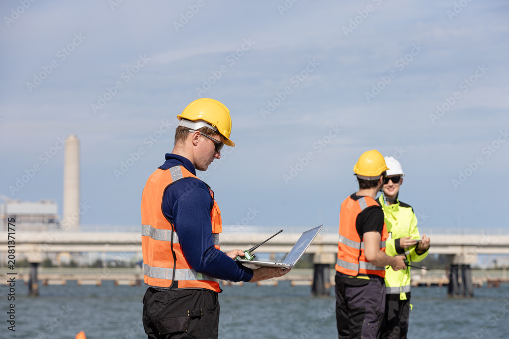 Fototapeta premium Engineers collaborating at an oil and gas refinery site with industrial infrastructure in the background