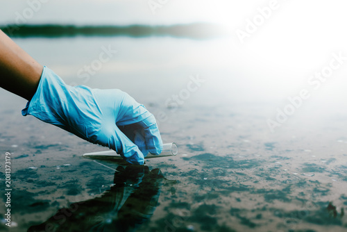 Scientist collecting water sample to monitor pollution and environmental quality.