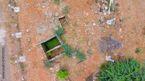 Cinematic top view of ancient megalithic burial site at Kodumanal, Tamil Nadu, India, with menhir standing stones, stone cist graves and red laterite earth revealing centuries-old history.