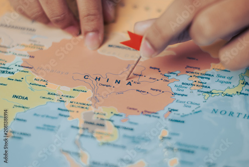 Woman indicating china on a world map using a pin to highlight its geographical location