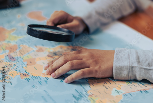 Woman examining a world map with a magnifying glass planning her next travel adventure