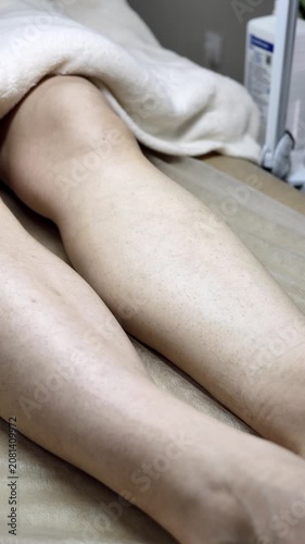 Professional specialist in black gloves cleans female legs with antiseptic before electrolysis procedure. Vertical close up shot. Concept of hygiene, safety and preparation in beauty clinic