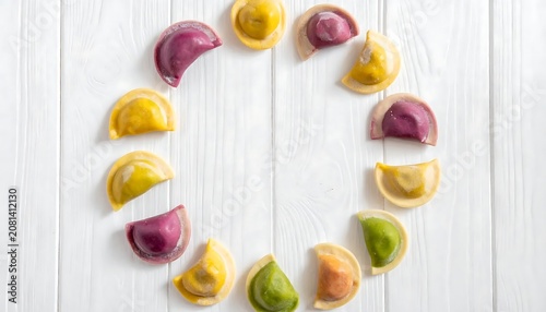 Colorful homemade dumplings arranged in a circle on a white wooden background.