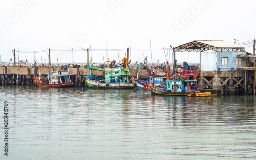 Traditional Thai Fishing Boats Moored at a Coastal Pier in the Gulf of Thailand. The authentic maritime lifestyle and local coastal industry with old Thai fishing boats docked at a concrete pier.