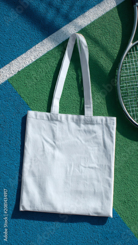White tote bag on colorful tennis court with racket shadow