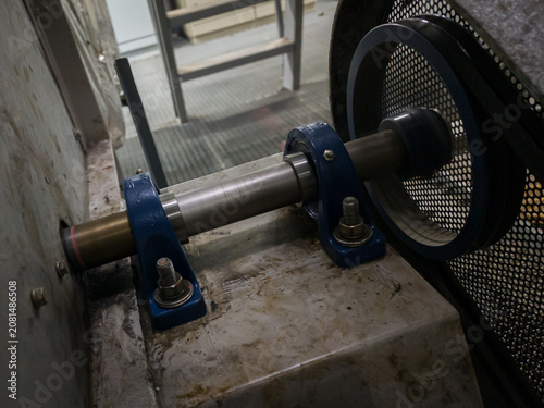 Industrial photo of rotating shaft with pulley, pillow block bearings, and belt guard in high-speed motion. Perfect for engineering, machine, and technical design themes.