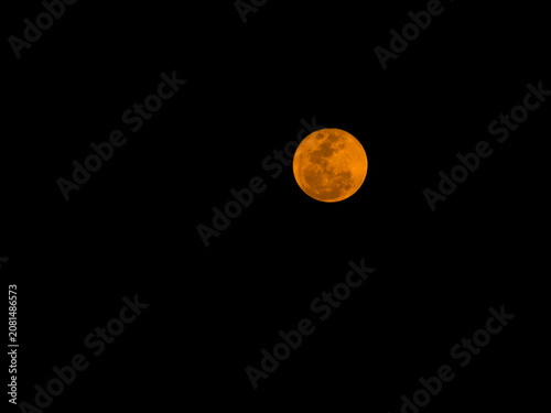 Close-up photo of bright orange full moon against dark night sky. Perfect for astronomy, nature, and atmospheric design themes.