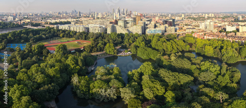 Canvas Print An ultra-wide panoramic aerial view looking across the lush green treetops, boating lake, and recreational sports grounds of Battersea Park toward the distant London cityscape