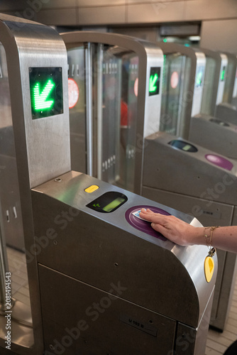 osoba skanująca kartę na bramce przy wejściu do metra