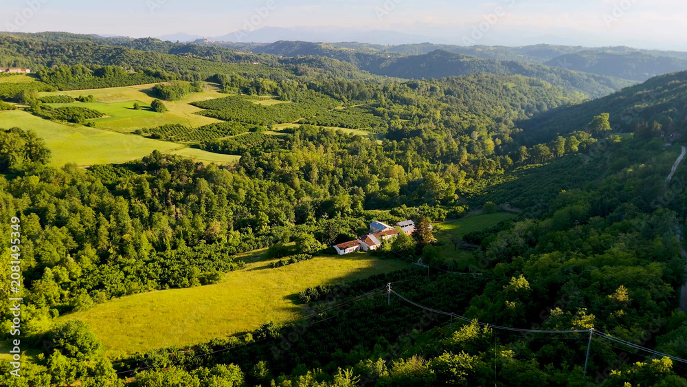 Fototapeta premium Aerial View of Lush Green Hills and Farmhouse in Piedmont Italy