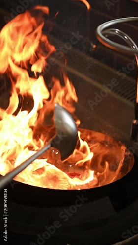 Cinematic vertical video of frying meat in a wok pan in slow motion. Chef stir-frying ingredients in a seasoned wok pan with fire flames. Cooking asian cuisine in a restaurant.