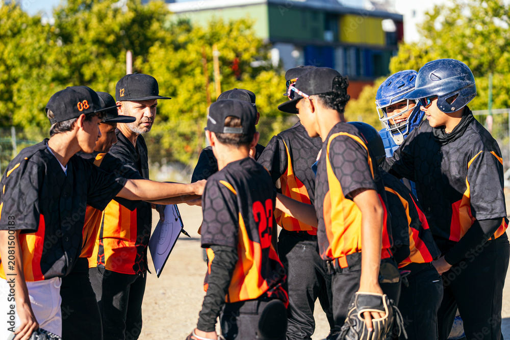 Obraz premium Coach and youth baseball team huddling together discussing strategy and building teamwork before a game