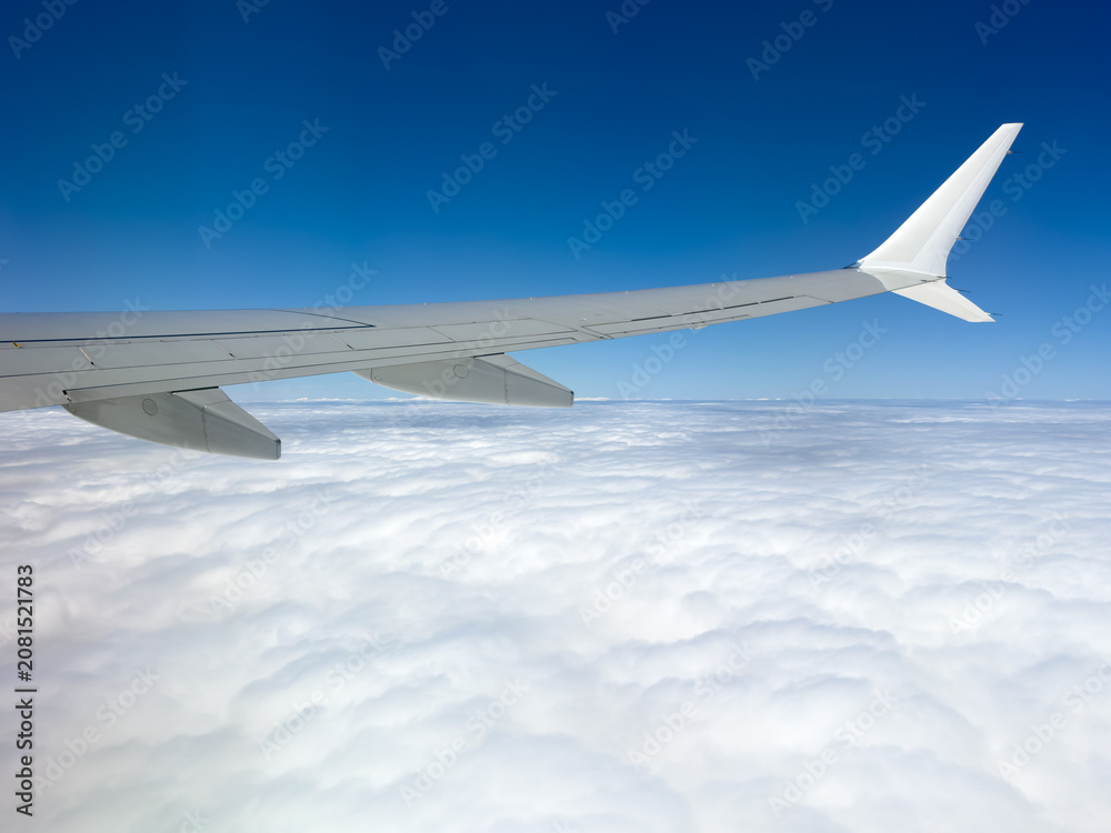 Obraz premium Airplane wing soars above cloud cover