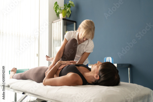 Cuadro en lienzo Female osteopath guiding gentle leg stretch for adult woman lying on treatment t