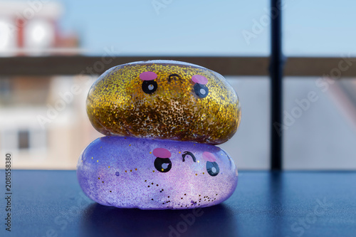 Gold and purple glitter squishy toys with smiling faces rest together on a tabletop. Sensory toy concept for stress relief, tactile play and cheerful childhood mood