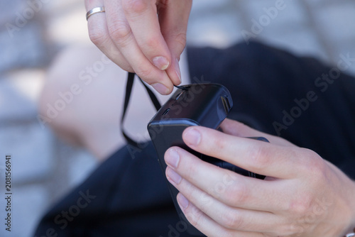 Φωτογραφία Hand attaching wrist strap to compact camera