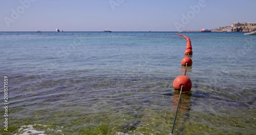 Slow motion footage of clear shallow seawater and orange buoys line leading toward the horizon creating a calm tropical beach atmosphere and peaceful summer holiday scenery in Sharm El Sheikh Egypt
