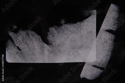 Torn Adhesive Label Residue Texture on Black Background