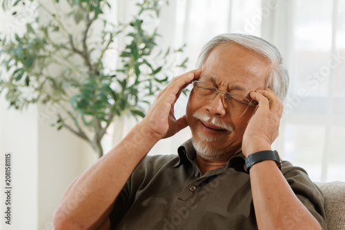 Cuadro en lienzo Elderly man suffering from headache while sitting at home