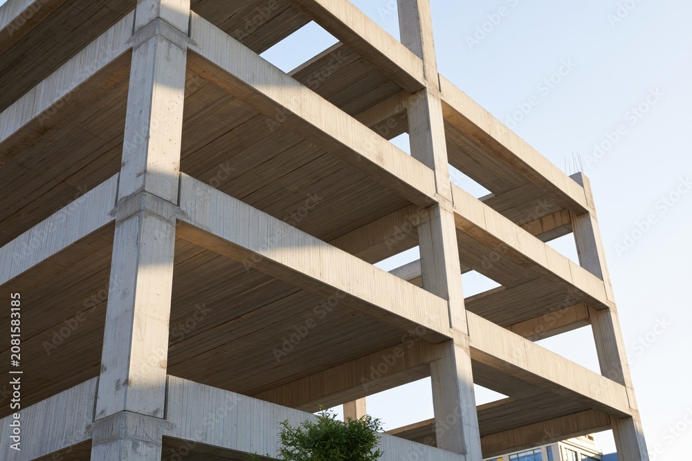 Obraz premium The unfinished concrete building skeleton under construction against a clear sky