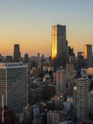 Modern Tokyo cityscape at dusk during the magic hour, featuring the illuminated Azabudai Hills skyscraper and surrounding city lights.