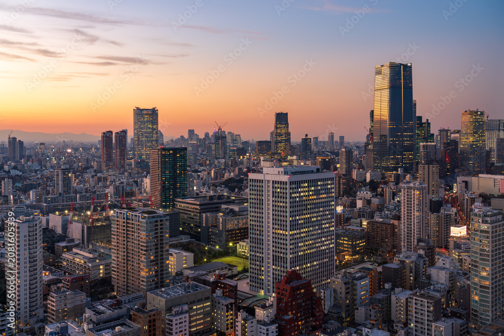 Fototapeta premium Modern Tokyo cityscape at dusk during the magic hour, featuring the illuminated Azabudai Hills skyscraper and surrounding city lights.