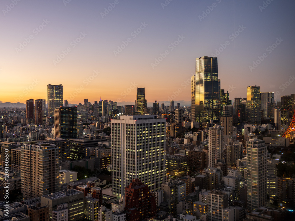 Fototapeta premium Modern Tokyo cityscape at dusk during the magic hour, featuring the illuminated Azabudai Hills skyscraper and surrounding city lights.