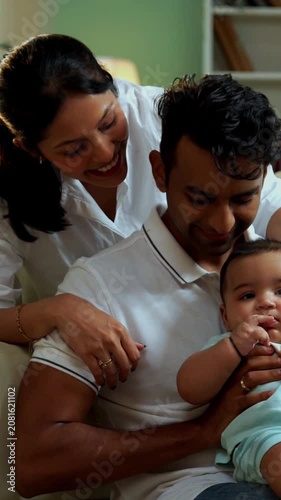 Parents sitting with baby boy while sitting on floor near sofa in modern living room, showcasing Indian family bonding, love, parenting, parenthood, emotional care, happy lifestyle, and cozy moments