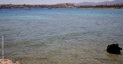 Slow motion footage of crystal clear waters of Naama Bay in Sharm El Sheikh Egypt stretching towards the coastline with resort buildings distant mountains and the colourful Red Sea
