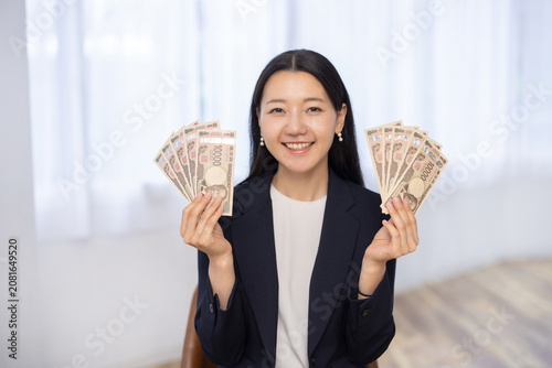 Εκτύπωση καμβά Young Japanese woman holding 100000 yen smiling at camera