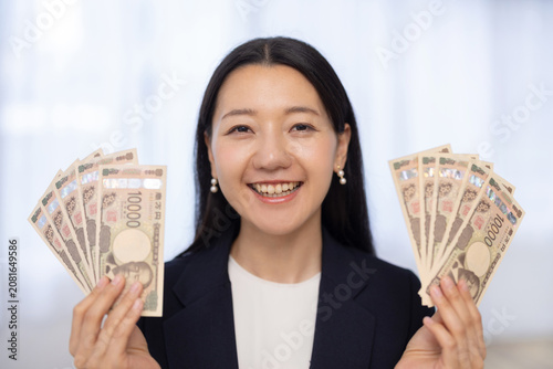 Fotografía Young Japanese woman holding 100000 yen smiling at camera