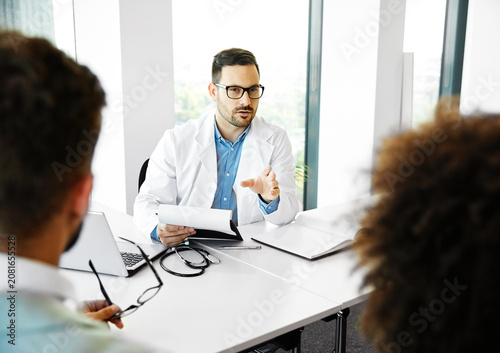 Принти на полотні Young doctor and young couple talking in office in the clinic or hospital