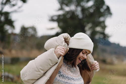 Vászonkép Woman outdoor winter jacket smiling, wearing a beanie and coat, enjoying a cold day in an open countryside landscape