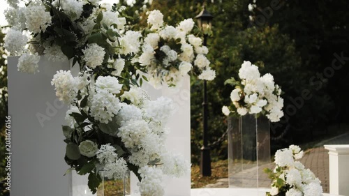 Wedding ceremony setting featuring elegant floral arrangements of white hydrangeas and greenery, beautifully arranged in a serene outdoor location