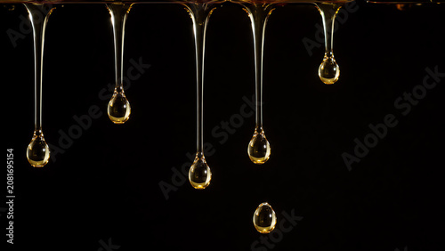 Golden syrup drips beautifully from a spoon against a dark background, creating an enticing and delicious visual appeal.