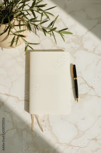 Blank Notebook and Pen on Marble Table With Plant During Daylight