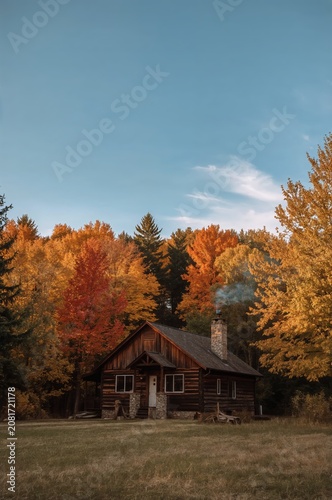 Log Cabin Stands in a Field Surrounded by Colorful Trees During Autumn