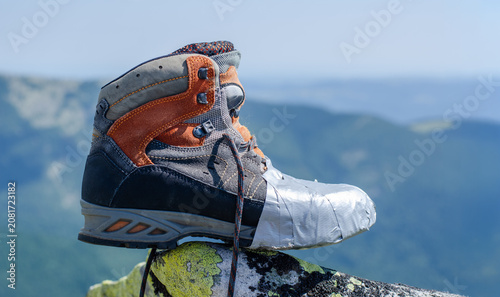 Hiking boots on a background of mountains. Boot wrapped with adhesive tape. Hiking