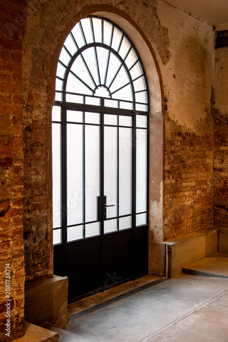 Schilderij op canvas Una grande porta a vetri protetta da una grata metallica all'interno di un vecch