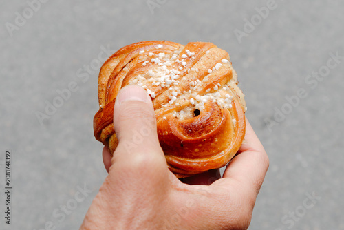 a close-up of a swedish kanelbulle held by a man