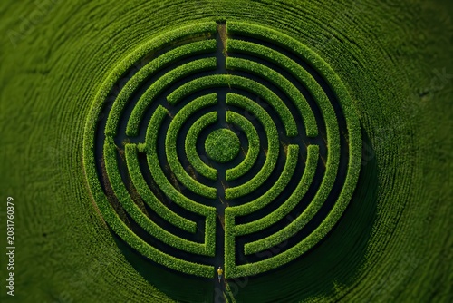 Aerial view of circular hedge maze in green field with geometric pattern