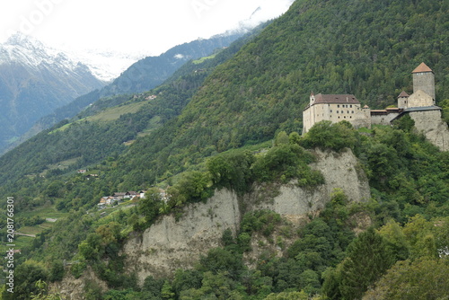 Historisches Schloss Tirol auf einem steilen Felsvorsprung vor alpiner Bergkulisse in Südtirol