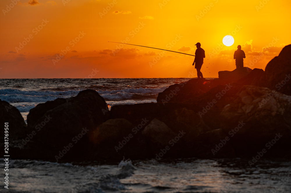 Fototapeta premium two silhouettes of fishers with ruffles against the backdrop of sunset