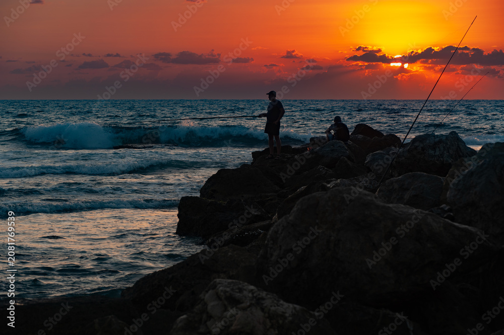 Fototapeta premium silhouette of two fishermans standing on a rock