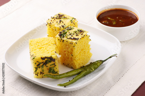Khaman Dhokla made up of rice chana dal is a popular breakfast or Snacks recipe from Gujarat, India, served with Green chutney and fried chilli.. Selective focus
