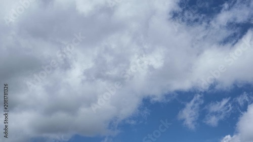 A serene, expansive sky with fluffy white clouds in continuous movement across it, capturing a peaceful atmosphere