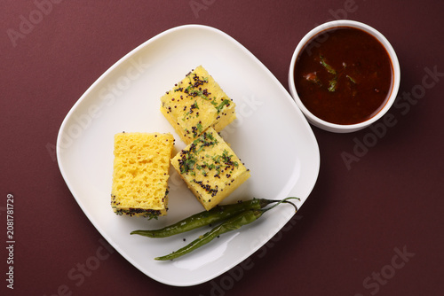 Khaman Dhokla made up of rice chana dal is a popular breakfast or Snacks recipe from Gujarat, India, served with Green chutney and fried chilli.. Selective focus
